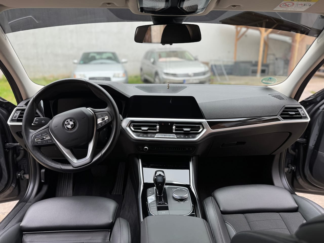 Frontale Ansicht des Armaturenbretts eines BMW 3er bei Tageslicht, sauberes Cockpit mit klarem Display.