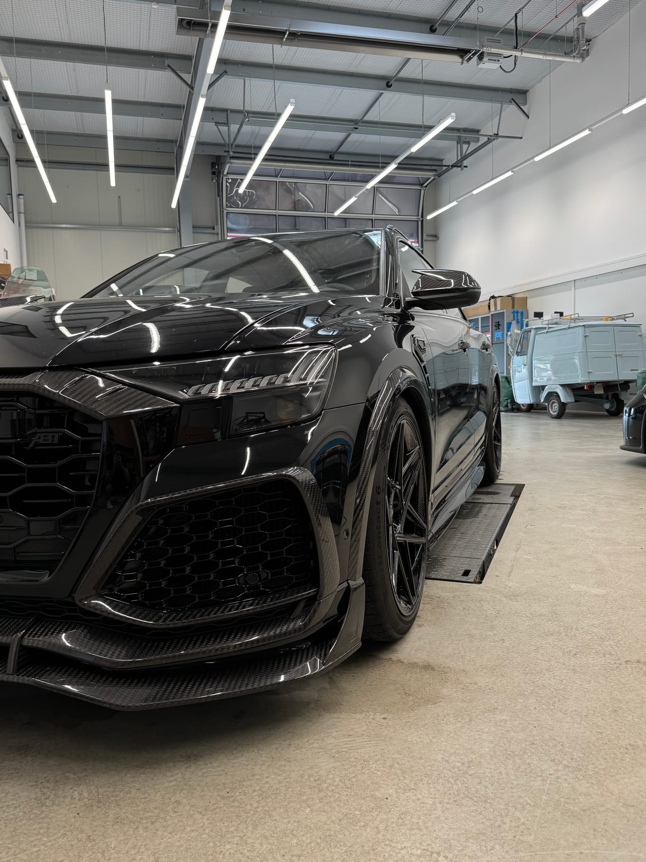 Schwarzer BMW mit Carbon-Frontgrill in der Aufbereitungshalle, Lack mit klaren Lichtreflexen.