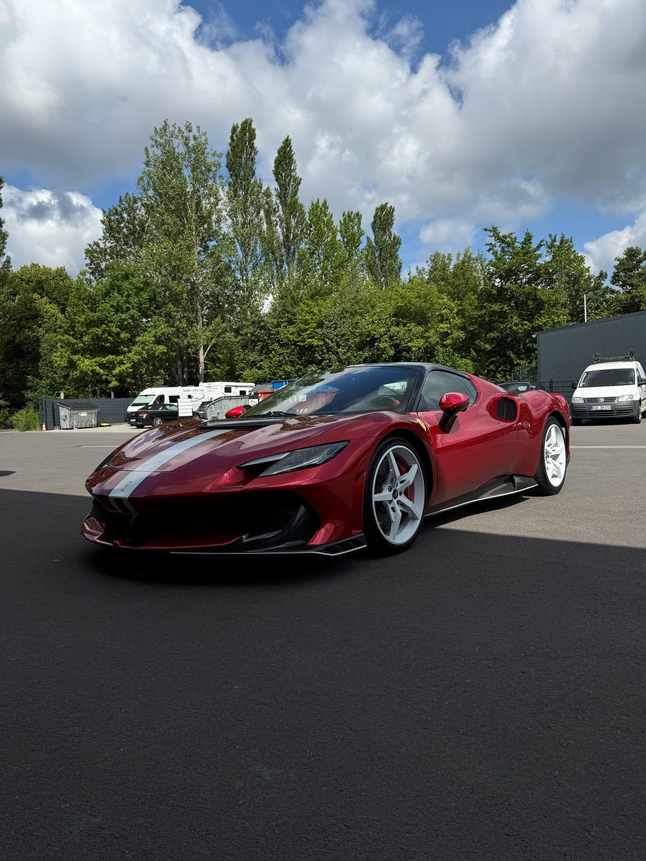 Dunkelroter Ferrari 296 mit weißem Rennstreifen nach der Außenaufbereitung, freistehend im Sonnenlicht mit tiefglänzendem Lack.