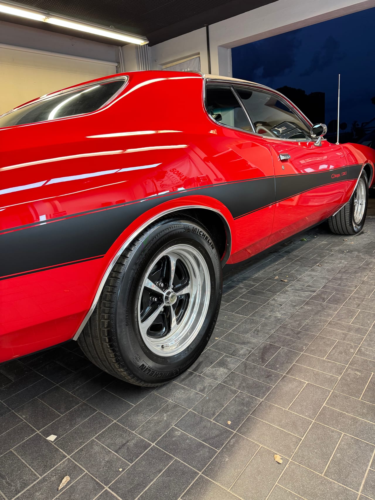 Roter Oldsmobile Cutlass Klassiker mit schwarzen Rallyestreifen nach der Aufbereitung im Studio, tiefglänzender Lack und polierte Chromfelgen.