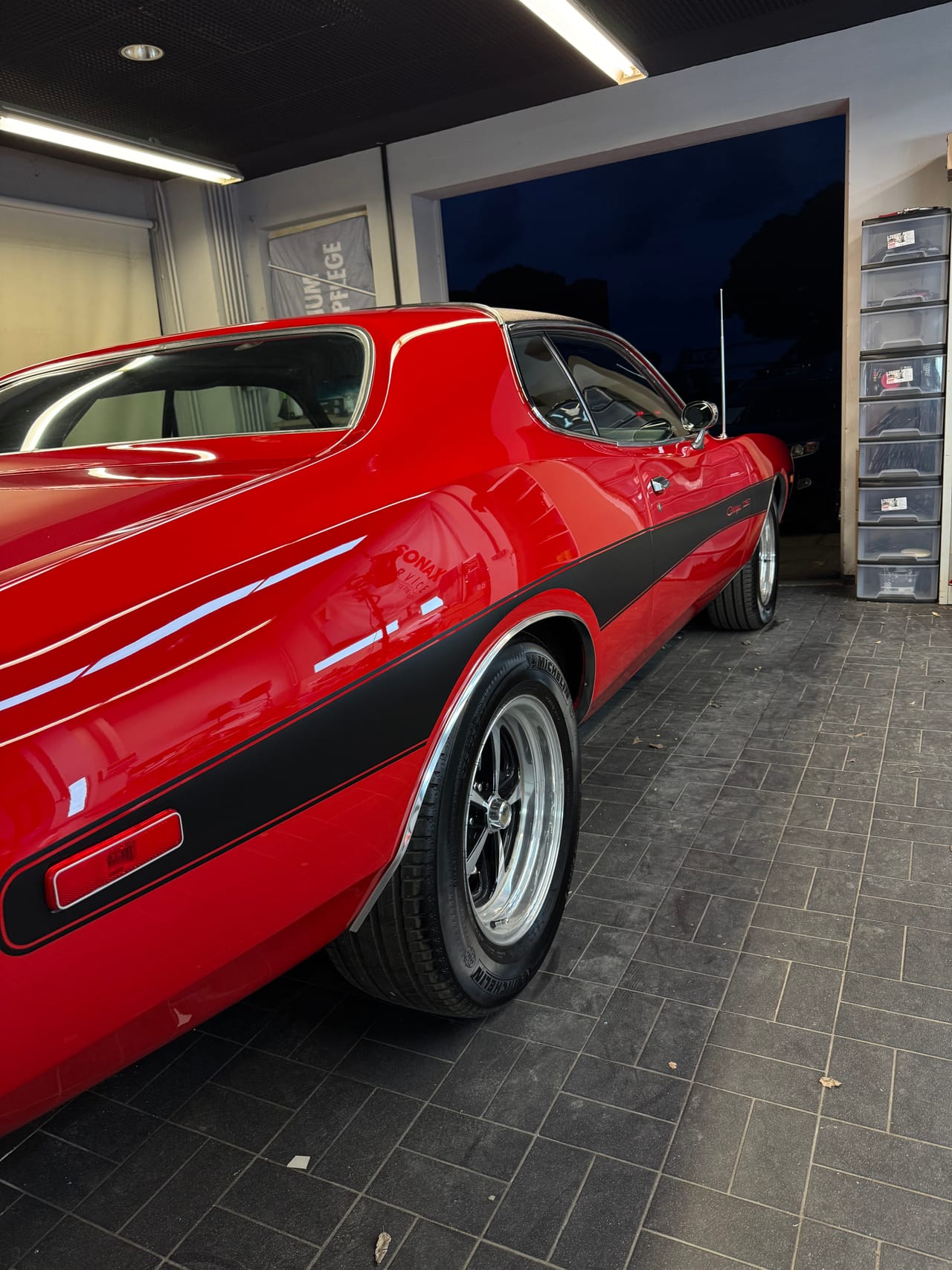 Heckpartie eines roten Oldsmobile Cutlass Klassikers mit schwarzem Streifendekor, frisch polierter Lack und glänzende Chromfelge nach der Politur.