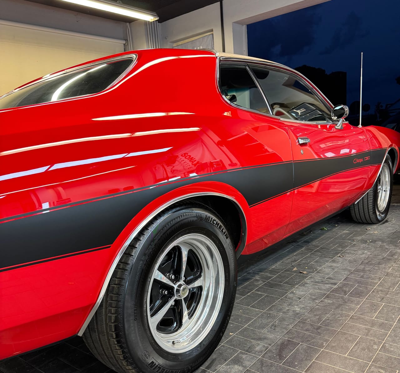 Roter Oldtimer-Klassiker mit schwarzen Rallyestreifen nach der Aufbereitung, tiefglänzende Seitenlinie mit Chromfelge im Studio.